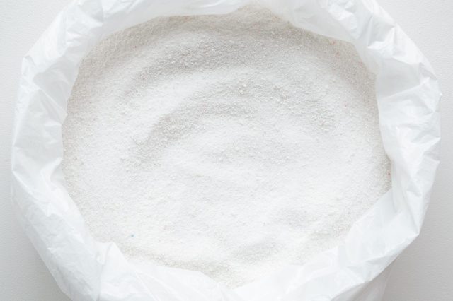 White powder sits inside an open plastic bag, suggesting storage or dispensing in a clean, neutral environment.