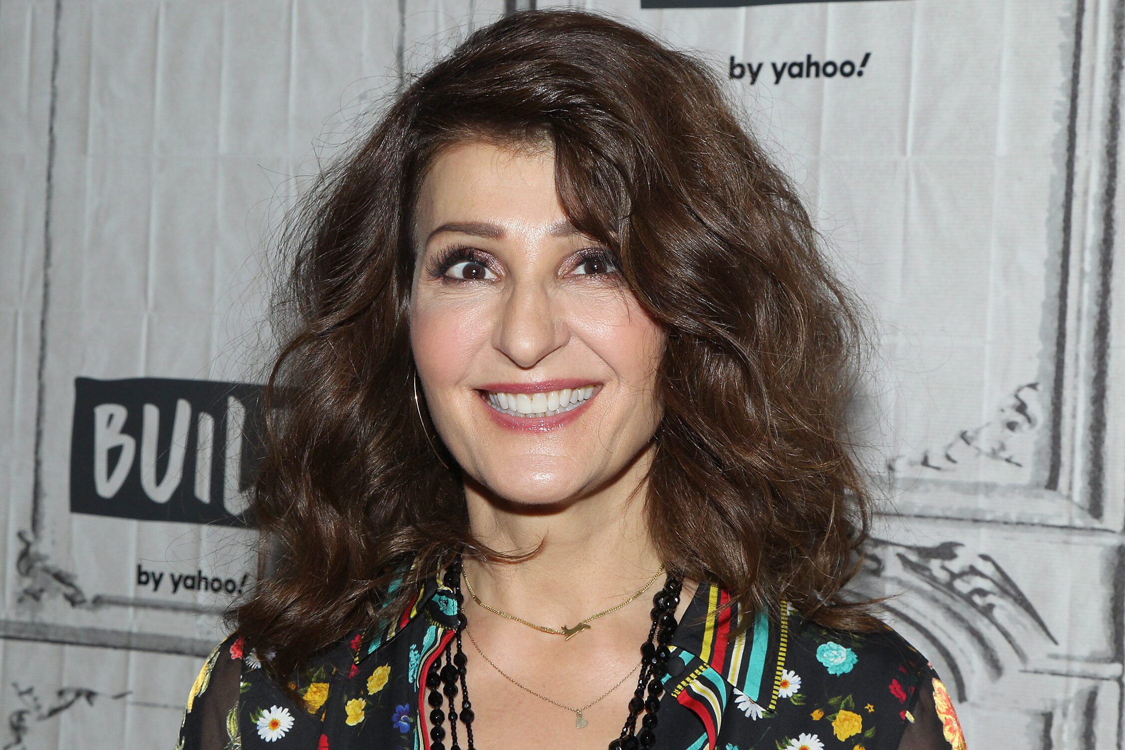 A person smiles, wearing a floral shirt, in front of a backdrop featuring "BUILD by yahoo!" text.