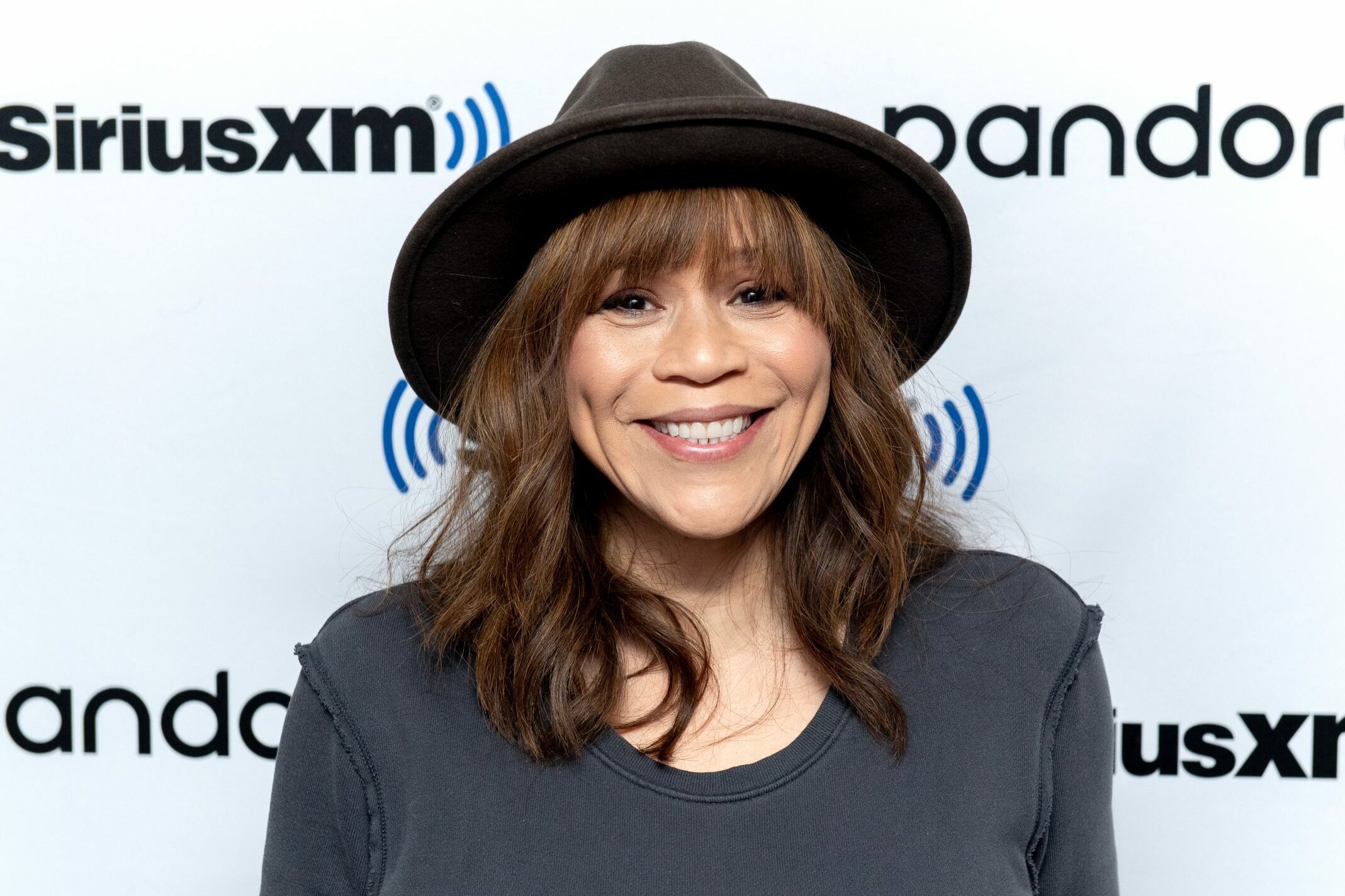 A person smiles wearing a black hat against a backdrop with "SiriusXM" and "pandora" logos.