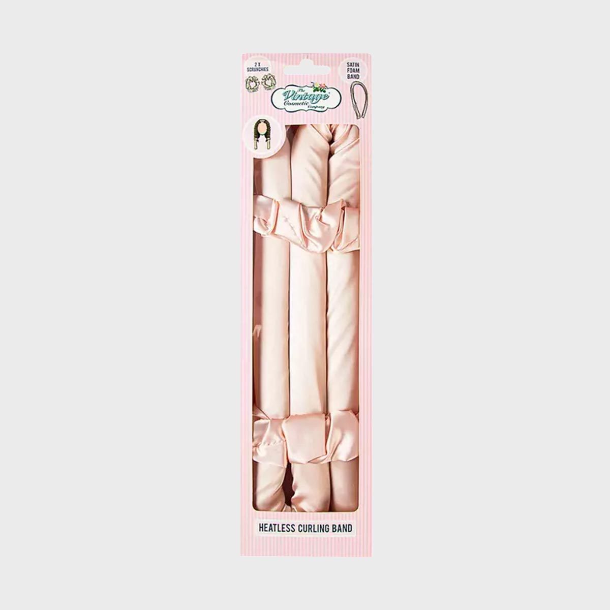 Pink satin hair bands rest inside clear packaging, displaying a "Heatless Curling Band" label against a light pink striped background.