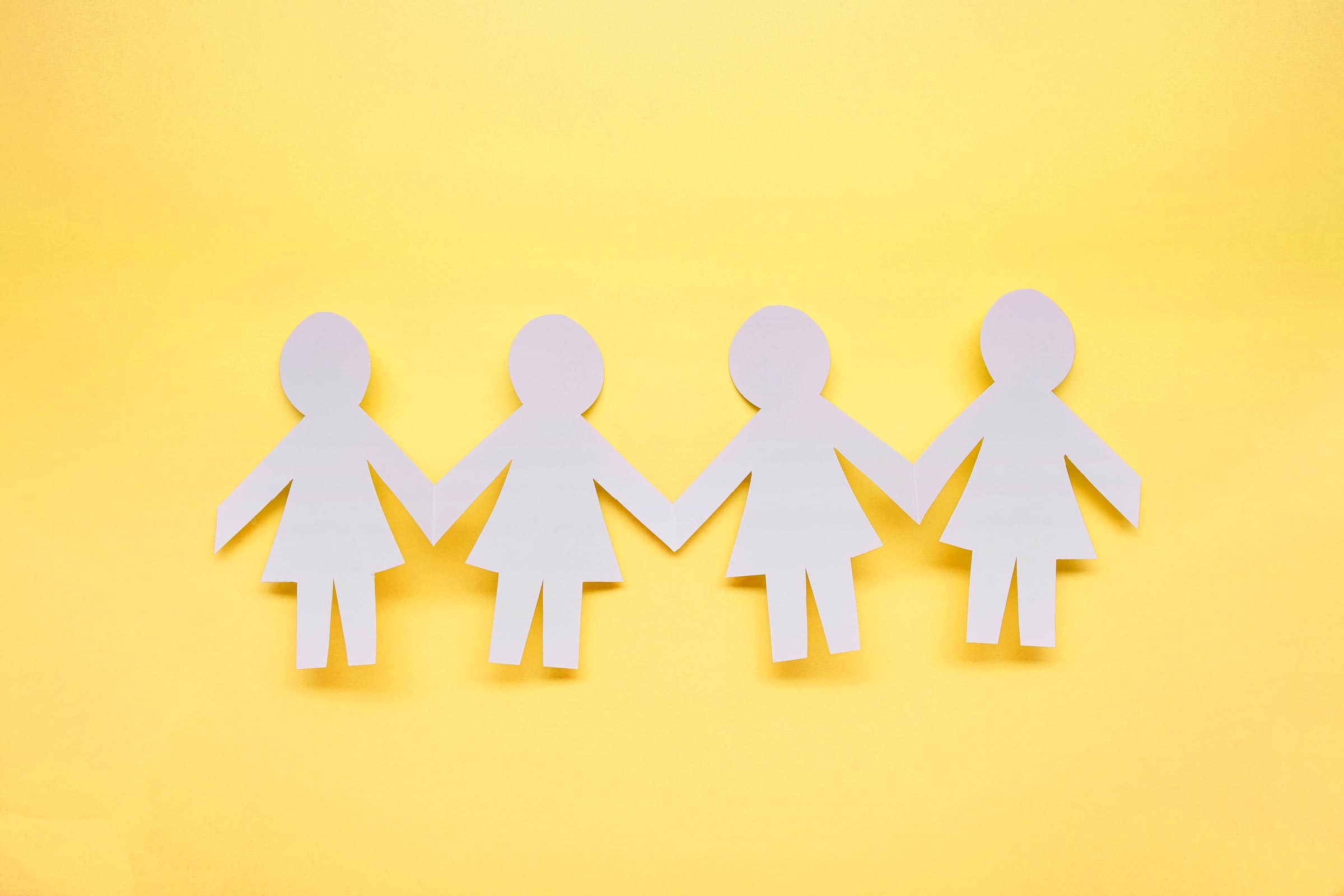 Paper Figures Hold Hands on a yellow background