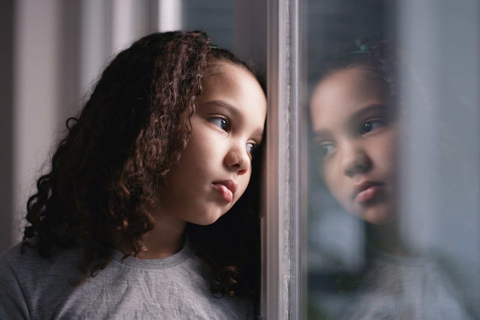 Mental health, girl and window for sad, thinking and depressed in home. Depression, black child and unhappy with stress, anxiety and frustrated with suffering, disappointed and foster female kid.