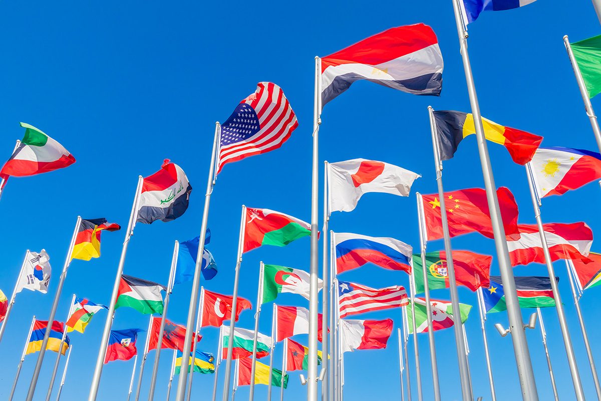 World congress countries national flags waving together on the wind, with American, Japanese, Omani, Chinese, Russian, Iraqi, Egyptian banners in the foreground
