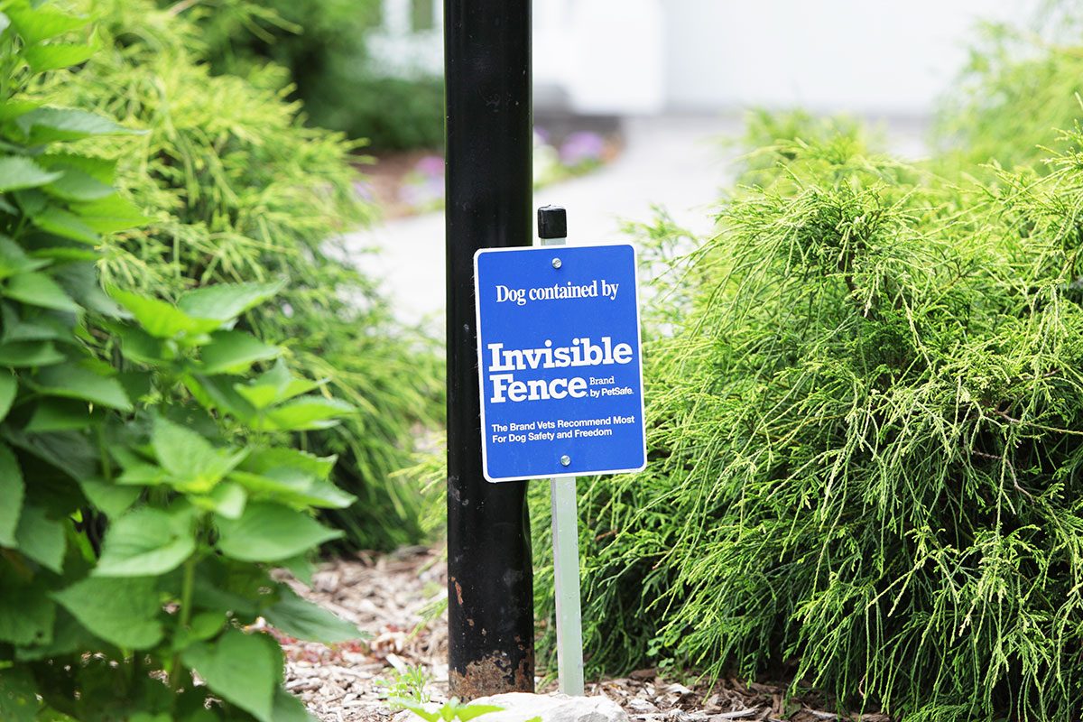 An Invisible Fence brand sign at a suburban residence